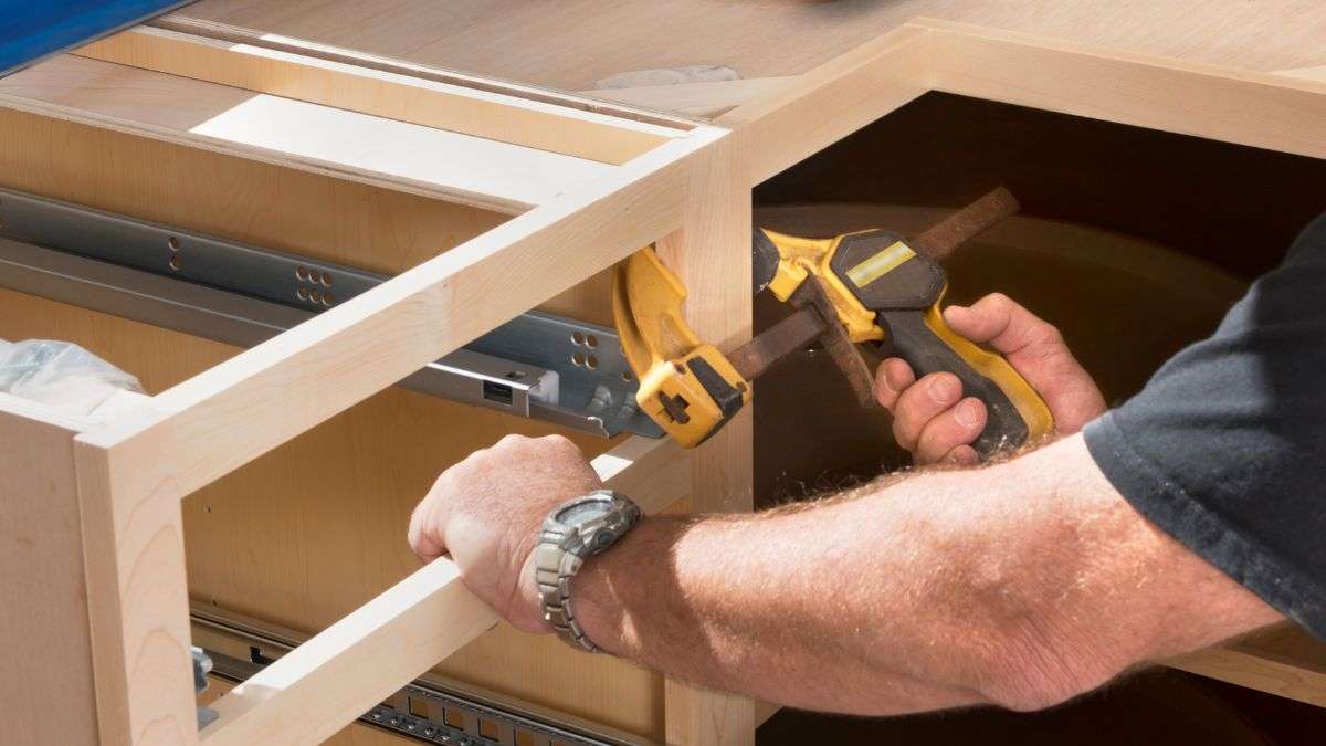 Close-up of clamping a drawer face inside a base cabinet during the process of building a woodworking shop