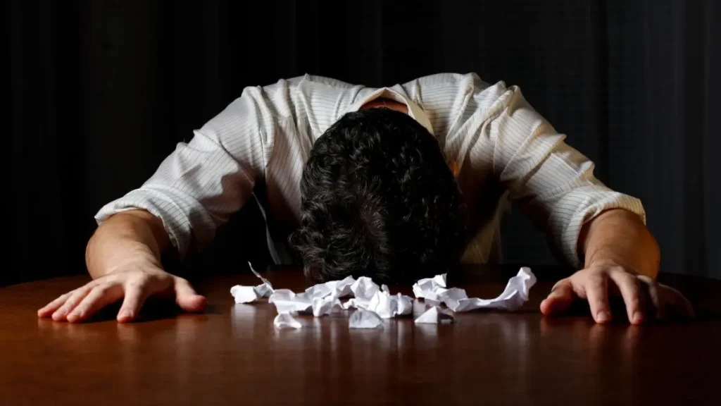 Person leaning forward in frustration with crumpled papers, illustrating how a space can work against your woodworking flow.