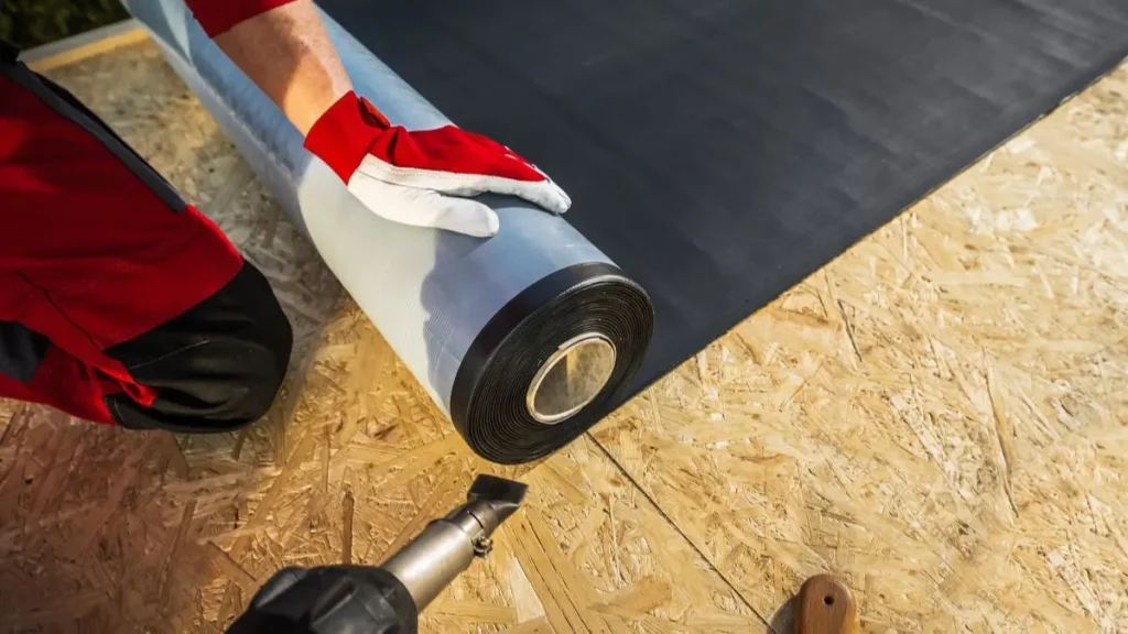 Rubber flooring roll being installed over OSB in a small workshop.