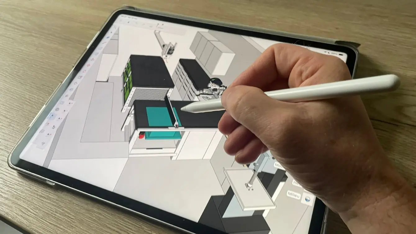 Hand using a stylus on a tablet to design a woodworking shop layout in SketchUp.