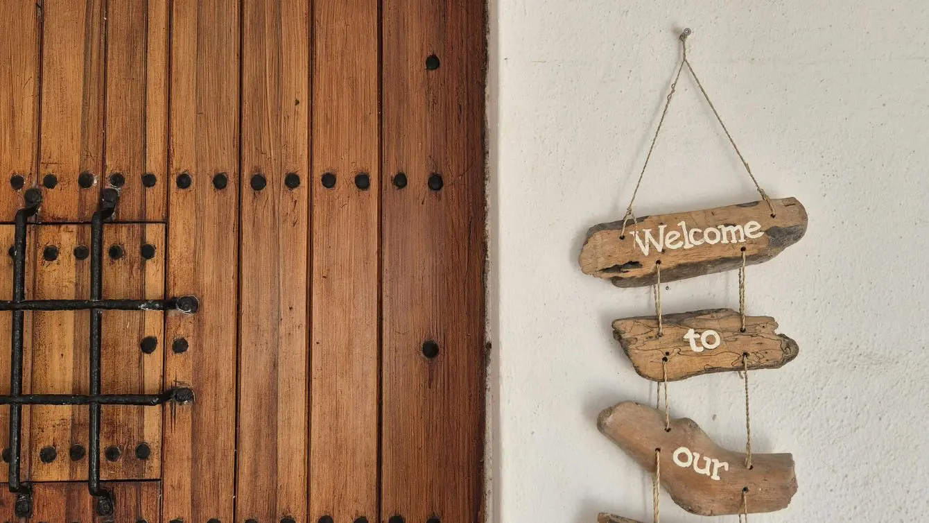 DIY home accessory made from driftwood with “Welcome” sign hanging on a wooden door.