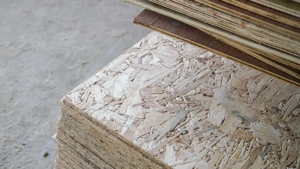 Stack of OSB panels in a workshop setting, useful when considering is plywood good for a workshop floor.