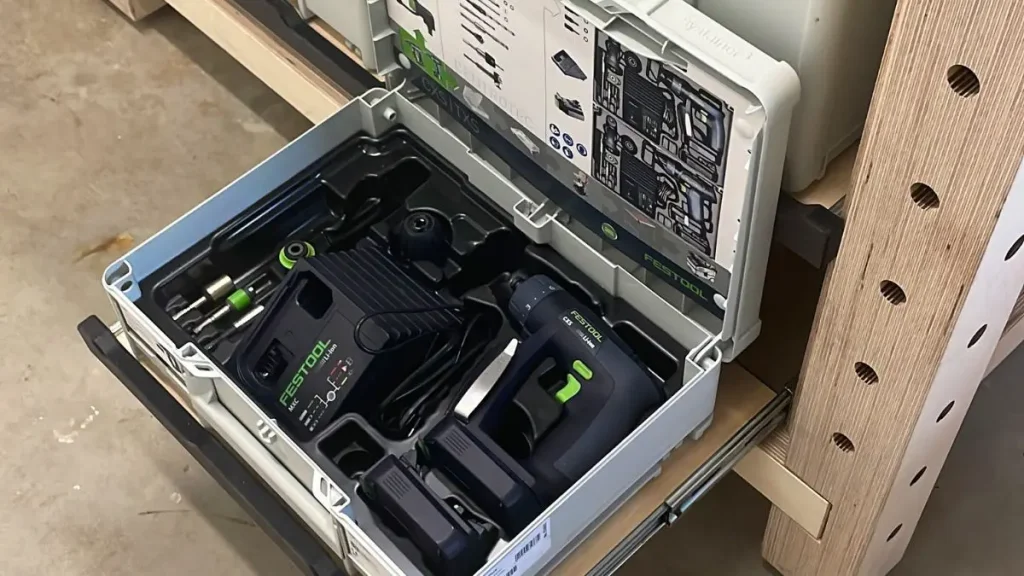 Storing power tools in a drawer system inside a small shed workshop.