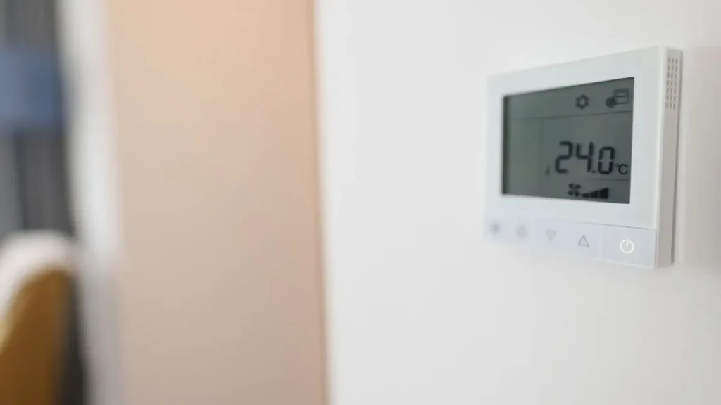 A wall thermostat showing room temperature in a workshop as part of preparing a woodworking shop.