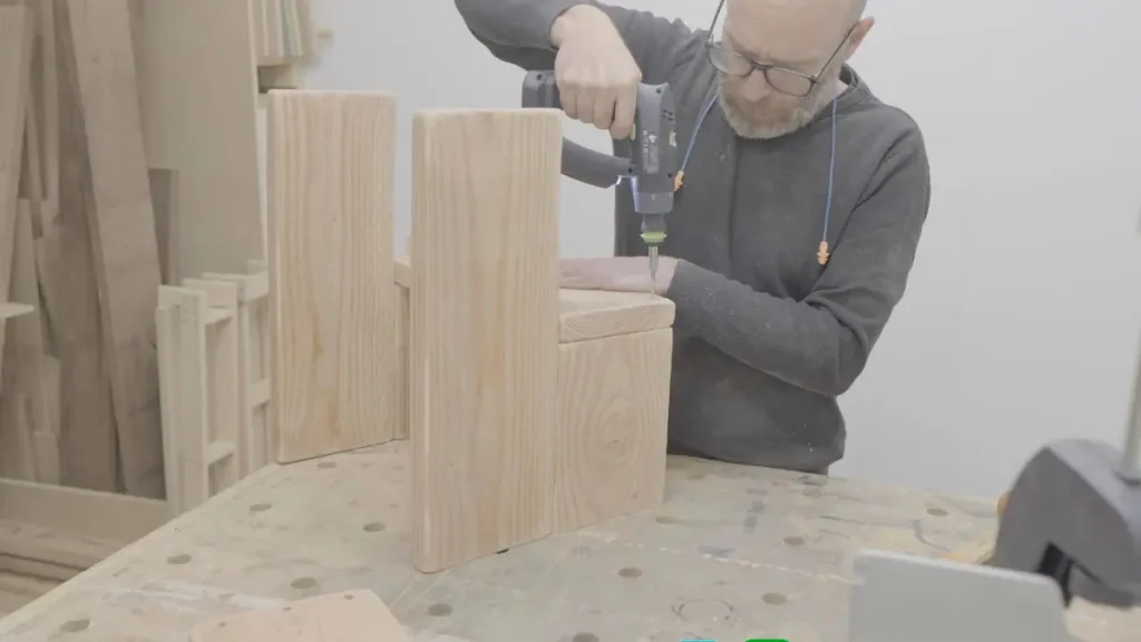 Woodworker using basic woodworking techniques to assemble a small project with a drill