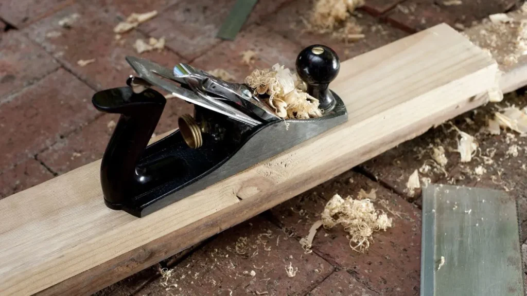 Hand plane shaving a board while demonstrating essential Woodworking Tools for beginners.