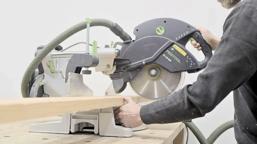 Using a miter saw to make accurate cuts as part of essential Woodworking Tools for beginners.