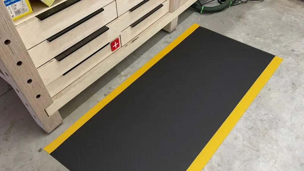 Anti fatigue mat placed in front of a woodworking workbench in a small garage shop