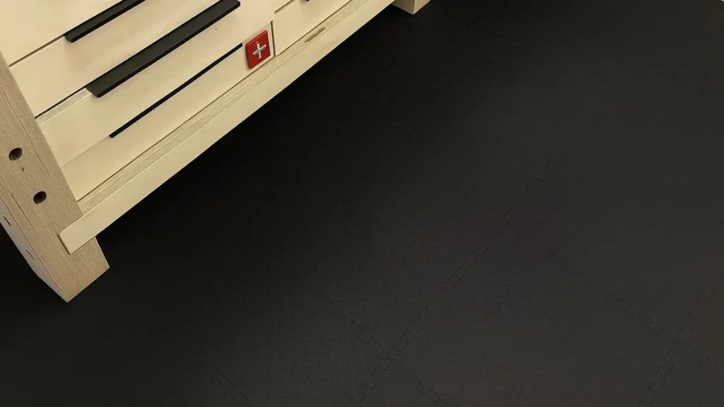 Black interlocking floor tiles installed in a small workshop, showing the pros and cons of interlocking floor tiles in real use.